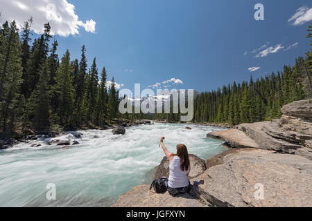 Un turista prende un selfie mentre appollaiato sul bordo di Mistaya Canyon, il Parco Nazionale di Banff, Canada Foto Stock