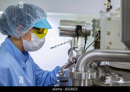 Tecnico farmaceutico opere sterili in condizioni di lavoro in fabbrica farmaceutica. Lavoratore di sesso femminile che di indossare abbigliamento protettivo. Foto Stock