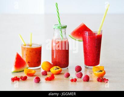 Vita Tranquilla con il frullato estivo bevande in bicchieri in tavola decorati con frutti e bacche - cocomero, albicocca, lampone, ribes rosso Foto Stock