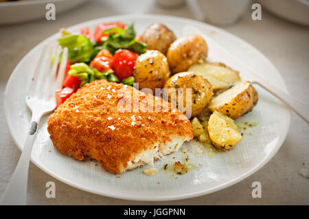 Panato tradizionale filetto di merluzzo con baby patate ed insalata Foto Stock