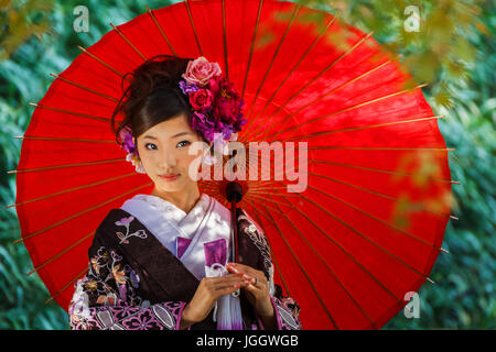 Donna Giapponese in un tradizionale abito Kimono con un ombrello rosso Foto  stock - Alamy