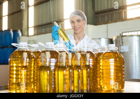 Tecnico femminile esaminando l' olio d' oliva in fabbrica Foto Stock
