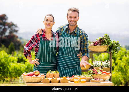 Ritratto di giovane coppia che vendeva verdura presso l'azienda Foto Stock