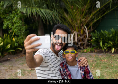 Giocoso padre e figlio indossando sunglases tenendo selfie Foto Stock