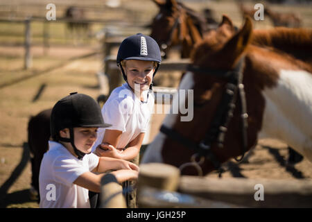 Ragazze sorridenti guardando il cavallo al ranch in una giornata di sole Foto Stock