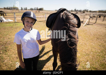 Ritratto di ragazza sorridente in piedi accanto al marrone a cavallo in un ranch in una giornata di sole Foto Stock