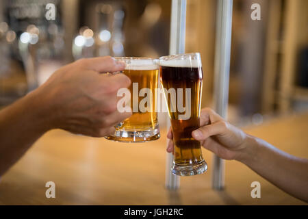 Close-up di coppie di tostatura a mano un bicchiere di birra al bar counter Foto Stock