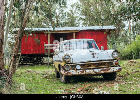 Punta Negra, Maldonado provincia, Uruguay - Giugno 29, 2017: Rusty vecchia auto parcheggiata di fronte a un vecchio carro merci ferroviario trasformato in una piccola casa Foto Stock