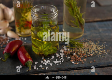 Peperoncino Jalapeno da spezie e erbe con olio in contenitori su di un tavolo di legno Foto Stock