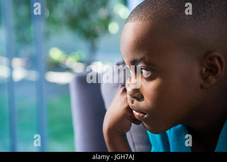 Close-up di pensosa boy contro la finestra a casa Foto Stock