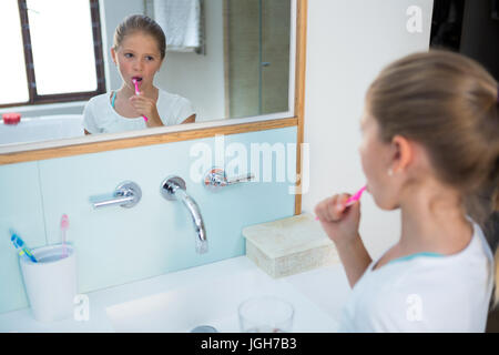 Angolo di Alta Vista della ragazza la spazzolatura dei denti mentre riflettendo a specchio Foto Stock