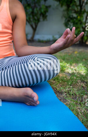 Immagine ritagliata della ragazza la meditazione seduti sul tappeto di esercizio in cantiere Foto Stock