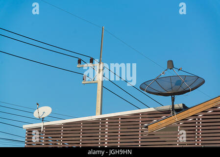 Grande Nero antenna parabolica sul tetto con l'azzurro del cielo e del cloud Foto Stock