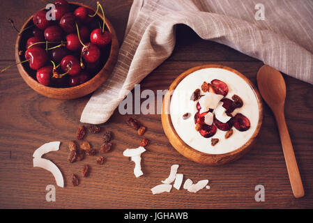 Fiocchi di avena con yogurt e frutta. Le ciliegie, uvetta e scaglie di cocco. Pernottamento Prima colazione. Cibo sano concetto. Fitness dieta dell'umore. Luce estiva SNA Foto Stock