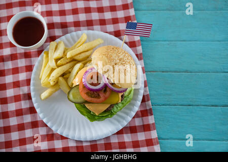 Vista aerea del cheeseburger con bandiera americana servita con patatine fritte sul tavolo Foto Stock