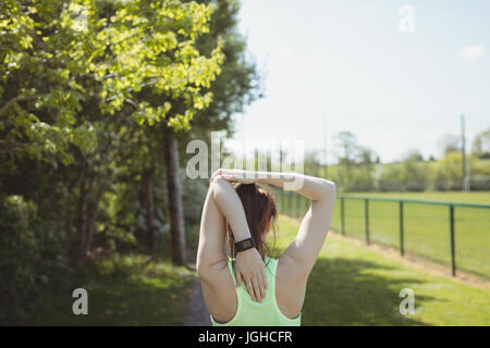Vista posteriore del giovane atleta femminile stretching per campo Foto Stock