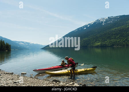 Coppia matura con kayak sul lungolago contro sky durante la giornata di sole Foto Stock