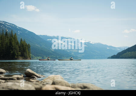 Distanza del giovane kayak nel lago in mezzo montagne contro il cielo Foto Stock