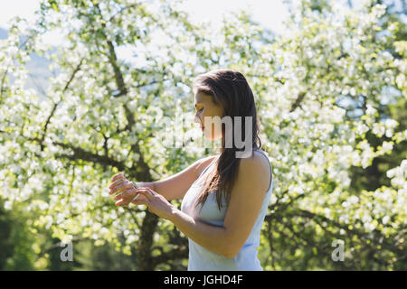 Donna che utilizza smartwatch in park in una giornata di sole Foto Stock