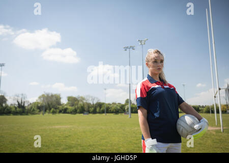 Giovani femmine goalie con pallone da calcio che guarda lontano sul campo Foto Stock