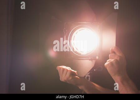 Mani tagliate del fotografo illuminato di regolazione luce stroboscopica allo studio Foto Stock