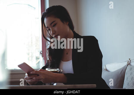 Bella donna utilizzando il telefono cellulare nel ristorante Foto Stock