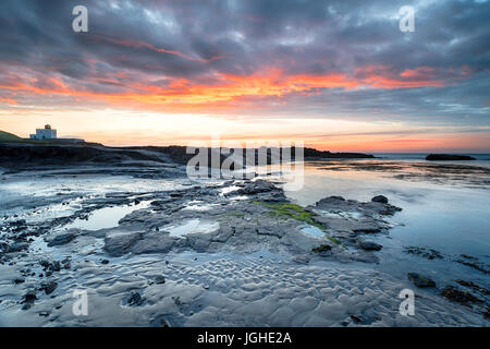 Il tramonto del faro e spiaggia a Bamburgh sulla costa di Northumberland Foto Stock