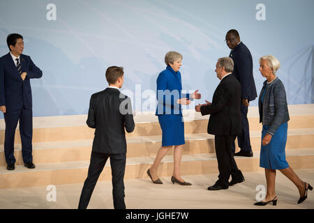 Il primo ministro Theresa Maggio saluta il Segretario Generale delle Nazioni Unite Antonio Guterres come i leader del mondo si riuniscono per una foto di famiglia durante il vertice del G20 di Amburgo. Foto Stock