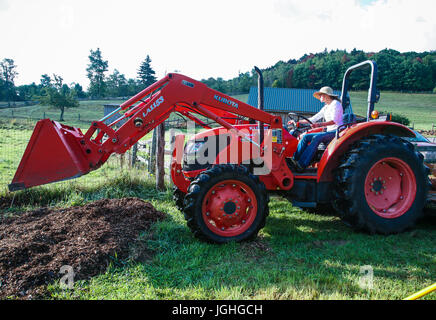 Donna giovane agricoltore sul trattore rosso Foto Stock