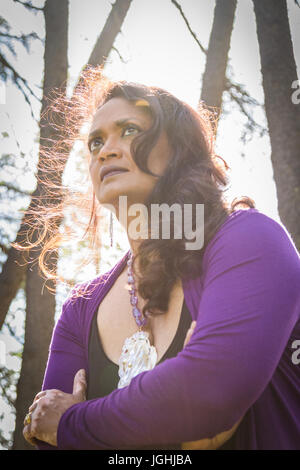 Medio-aged​ donna con espressione seria colpo dal basso con grave lens flare attraverso i capelli Foto Stock