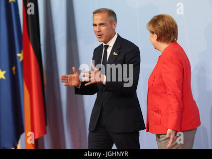 Il cancelliere tedesco Angela Merkel accoglie il Presidente del G20's Financial Stability Board (FSB) Mark Carney durante il vertice del G20 a Amburgo, Germania. Foto Stock