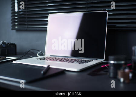 Lo spazio di lavoro sulla tavola nera di un fotografo o designer con il computer portatile , retrò fotocamera , elegante home studio concetto di hipster . Scelti focus. Foto Stock