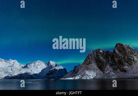 Cielo stellato con luci del nord ofer ripida e coperta di neve montagne rocciose in Norvegia del nord in inverno Foto Stock