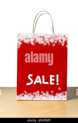 Un inverno o vendita di Natale shopping bag in rosso con il simbolo del fiocco di neve bianca a bordi superiore e inferiore e la parola 'SALE!' nella metà inferiore con spazio di copia Foto Stock