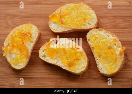 Cibatta piccole fette di pane con Siviglia marmellata di arance sulla scheda di bambù in formato orizzontale Foto Stock