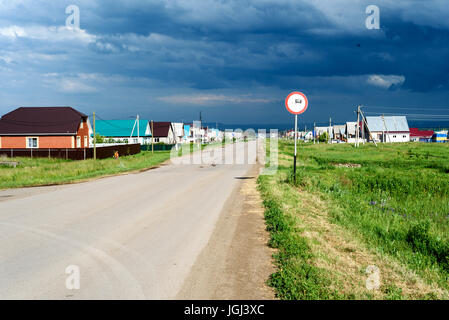 Svuotare polverosa strada russo con un cielo tempestoso e un cartello stradale per veicoli industriali pesanti Foto Stock