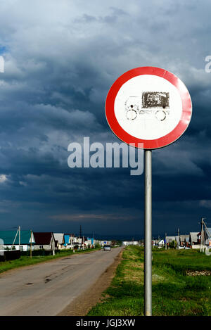 Svuotare polverosa strada russo con un cielo tempestoso e un cartello stradale per veicoli industriali pesanti Foto Stock