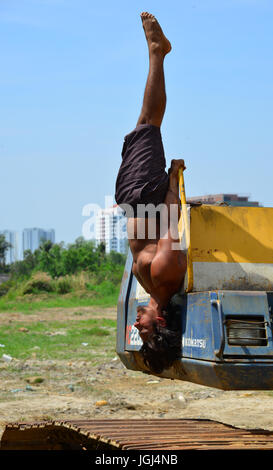 Delhi, India - Mar 9, 2017. Un indiano giovane uomo fare Yoga pone sulla costruzione macchina a tempo rilassante a Delhi, India. Foto Stock