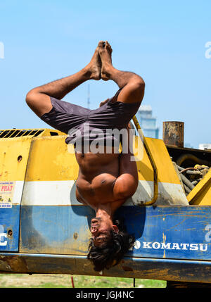 Delhi, India - Mar 9, 2017. Un indiano giovane uomo fare yoga esercizio sulla macchina di costruzione al tempo rilassante a Delhi, India. Foto Stock