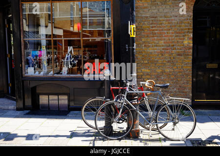 Biciclette parcheggiate fuori un negozio nel documento Wilkes Street in Shoreditch, nell'East End di Londra. Il negozio ha una vendita a. Foto Stock