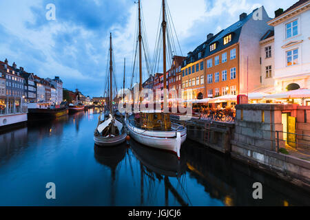Copenhagen Nyhavn (Nuovo Porto) distretto con le luci della città dopo il tramonto durante l ora di blu di legno di nave a vela e ristoranti, Danimarca Foto Stock