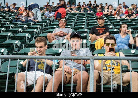 Detroit, Michigan - ragazzi adolescenti sono incollati ai loro telefoni cellulari durante una Detroit Tigers baseball gioco al Comerica Park. Foto Stock