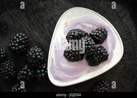 More con yogurt nero su sfondo di legno. Close up Foto Stock