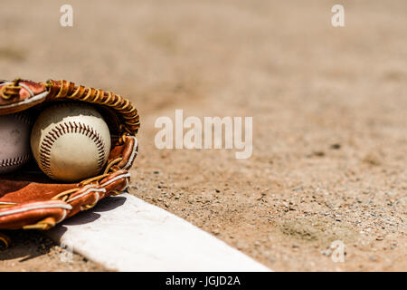 Baseballs in un Guanto baseball su un bricco di cumulo Foto Stock