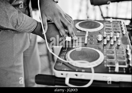 African American dj in enormi cuffie bianche creazione di musica su pannello di miscelazione. Foto in bianco e nero. Foto Stock