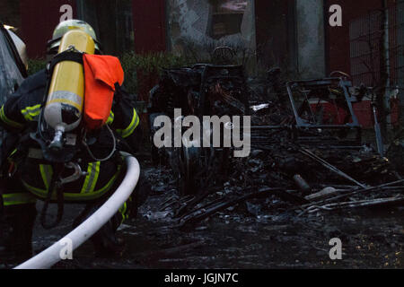 Amburgo, Germania. Il 6 luglio, 2017. St Pauli/Hamburg - Germania Luglio 6, 2017: pompiere il raffreddamento dei resti di una vettura che è stata impostata sul fuoco da sinistra-winged attivisti. Credito: Eva Agata Draze/Alamy Live News Foto Stock