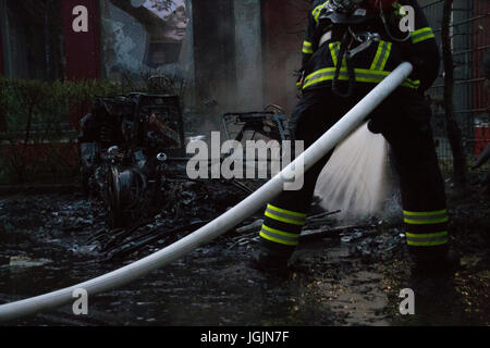 Amburgo, Germania. Il 6 luglio, 2017. St Pauli/Hamburg - Germania Luglio 6, 2017: pompiere il raffreddamento dei resti di una vettura che è stata impostata sul fuoco da sinistra-winged attivisti. Credito: Eva Agata Draze/Alamy Live News Foto Stock