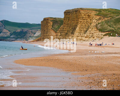 Burton Bradstock, Dorset, Regno Unito. 8 luglio 2017. Le persone che si godono la spiaggia con il famoso West Bay scogliere come uno sfondo come il soleggiato clima caldo prosegue sulla costa sud. Credito: Dan Tucker/Alamy Live News Foto Stock