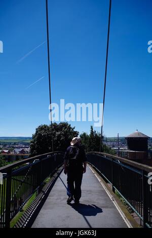 Uomo a piedi attraverso il ponte pedonale di Yaroslavl in un giorno estivo soleggiato. Exeter, Devon, Regno Unito. Luglio 2017. Foto Stock