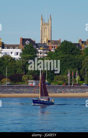 Barca da diporto a vela dirigendosi verso l'interno passando per Exmouth e la Chiesa della Santissima Trinità da Dawlish Warren, Devon, Regno Unito. Luglio, 2017. Foto Stock